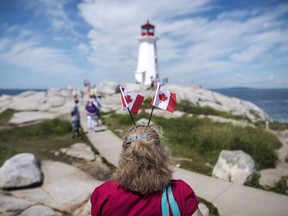 Nicole Freeman, of Montreal, wears two Canadian flags in her hair while visiting the lighthouse in Peggy's Cove, N.S., on Canada Day, July 1, 2016. Five iconic tourism sites in Nova Scotia including Peggy's Cove and the Cabot trail are getting a total of $6 million over three years for tourism infrastructure projects.THE CANADIAN PRESS/Darren Calabrese