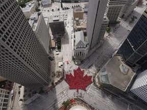 Winnipeggers celebrate Canada's 150th birthday by forming a "Living Leaf" at the historic downtown intersection of Portage and Main, in Winnipeg on July 1, 2017. For decades, Winnipeg residents have debated the idea of allowing pedestrians to once again cross a downtown intersection many consider iconic. This fall, they may be able to vote on it. Mayor Brian Bowman announced Wednesday he supports including a referendum question in the upcoming municipal election on whether to remove the concrete barriers that prevent people from crossing the road at Portage Ave and Main St.