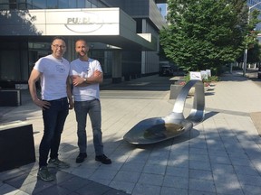 FILE - In this June 22, 2018 file photo, art gallery proprietor Luis Alvarez, left, and sculptor Domenic Esposito, right, stand beside an 800-pound sculpture of a bent, burnt heroin spoon placed in front of the Stamford, Conn., headquarters of Purdue Pharma, to protest the company's manufacture of opioids. Alvarez is due to be arraigned in Stamford on Tuesday, July 10, 2018, on a charge of interfering with police.