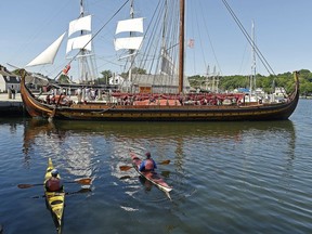 Two kayakers watch as the replica Viking ship Draken Harald Harfagre prepares to depart Chubb's Wharf at Mystic Seaport Museum for the start of its East Coast Tour, Monday, July 9, 2018, in Mystic, Conn.