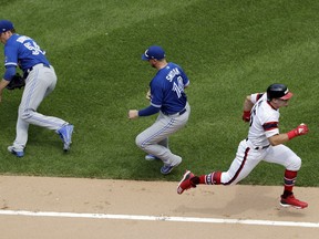 Chicago White Sox's Adam Engel, right, runs to first base after hitting a bunt-single as Toronto Blue Jays starting pitcher Ryan Borucki, left, and first baseman Justin Smoak field the ball during the fifth inning of a baseball game Sunday, July 29, 2018, in Chicago.