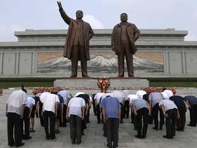 North Korean men bow at the giant bronze statues of late North Korean leaders Kim Il Sung and his son Kim Jong Il during the commemoration of the 65th anniversary of the ceasefire armistice that ended the fighting in the Korean War,  which the country celebrates as the day of "victory in the fatherland liberation war" at Mansu Hill Grand Monument in Pyongyang, North Korea, Friday, July 27, 2018.