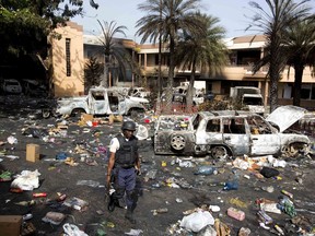 A police officer walks through the parking lot of the Delimart supermarket complex, where vehicles sit charred and looted merchandise lies scattered after two days of protests against a planned hike in fuel prices in Port-au-Prince, Haiti, Sunday, July 8, 2018.