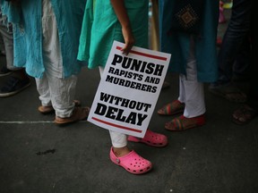 FILE - In this April 15, 2018 file photo, an Indian protestor stands with a placard during a protest against two recently reported rape cases as they gather near the Indian parliament in New Delhi, India. Police in eastern India have on Friday, July 6, arrested a school principal, two teachers and three students after a teenage girl blamed them and another 13 schoolmates for repeatedly raping her for last seven months. Reports of rapes of women highlight the persistence of such violence in India despite a public outcry following the December 2012 fatal gang rape of a young woman in New Delhi.