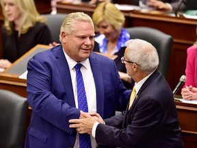 Ontario Premier Doug Ford shakes hands with Finance Minister Vic Fedeli following the speech from the throne at Queen's Park in Toronto on July 12, 2018.