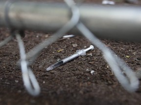 A discarded needle sits behind a fence by a safe-injection site on Victoria Street in downtown Toronto on July 4, 2018.