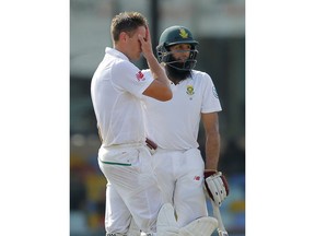 South Africa's Theunis de Bruyn, wipes his face as Hashim Amla awaits a third umpire decision during the day three of their second test cricket match with Sri Lanka in Colombo, Sri Lanka, Sunday, July 22, 2018.