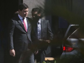Brazil's Labor Minister Helton Yomura, left, exits a federal police office in Brasilia, Brazil, Thursday, July 5, 2018. A Brazilian Supreme Court justice has ordered Yomura's suspension as part of a corruption investigation. Federal prosecutors say they are investigating fraud in the registration process for unions and allege that civil servants and lawmakers manipulated licensing.