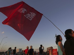 A supporter of Brazil's former President Luiz Inacio Lula da Silva carries a flag with text written in Portuguese that reads "Free Lula" during a protest in front of the headquarters of the Brazilian Supreme Court, in Brasilia, Brazil, Monday, July 9, 2018. The president of a Brazilian appeals court whose judges had issued contradictory rulings on whether former President Luiz Inacio Lula da Silva should be freed from jail has ordered that he remain in custody.