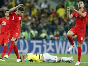 Colombia's Radamel Falcao, center, lies on the pitch after challenging for the ball with England's John Stones, left, during the round of 16 match between Colombia and England at the 2018 soccer World Cup in the Spartak Stadium, in Moscow, Russia, Tuesday, July 3, 2018.