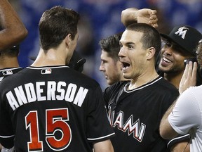 Miami Marlins catcher J.T. Realmuto, second from left, is congratulated by teammates after he drove in the winning run during the 10th inning against the Washington Nationals in a baseball game Saturday, July 28, 2018, in Miami. The Marlins won 2-1.