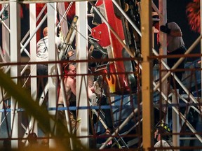 FILE - In this June 14, 2018, file photo, Daytona Beach Fire Department personnel rescuing riders from a roller coaster car that derailed in Daytona Beach, Fla. Investigators say excessive speed caused the roller coaster to derail.  Florida Agriculture Commissioner Adam Putnam says a preliminary investigation determined that excessive and operator error caused the Sand Blaster Roller Coaster at the Daytona Beach Boardwalk to derail.