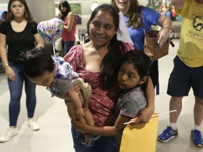 Buena Ventura Martin-Godinez, center, holds her son Pedro, left, as she is reunited with her daughter Janne, right, at Miami International Airport, Sunday, July 1, 2018, in Miami. Martin crossed the border into the United States from Mexico in May with her son, fleeing violence in Guatemala. Her husband crossed two weeks later with their 7-year-old daughter Janne. All were caught by the Border Patrol, and were separated. Her daughter was released Sunday from a child welfare agency in Michigan.