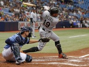 Miami Marlins' Miguel Rojas follows through on a double that knocked in three runs in front of Tampa Bay Rays catcher Adam Moore during the second inning of a baseball game Sunday, July 22, 2018, in St. Petersburg, Fla.