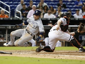Milwaukee Brewers' Christian Yelich (22) slides into home to score on a single by Travis Shaw, as Miami Marlins catcher Bryan Holaday waits for the throw during the eighth inning of a baseball game, Monday, July 9, 2018, in Miami. The Marlins defeated the Brewers 4-3 in 10 innings.