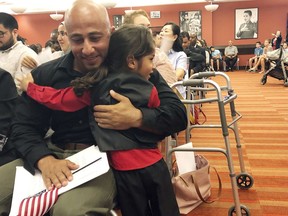 Haeder Al Anbki hugs his son Alasaad, during a naturalization ceremony in Orlando, Fla., Tuesday, July 31, 2018. Al Anbki, a former Iraqi translator and Florida National Guard member, sued a federal agency after he was pulled out of a naturalization ceremony last year without explanation. The lawsuit claimed authorities were applying a different set of rules under a program that opponents say targets applicants from majority-Muslim countries.