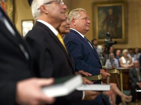 Doug Ford, Ontario's premier, right, holds a bible during a swearing-in ceremony in Toronto, Ontario, Canada, on Friday, June 29, 2018.