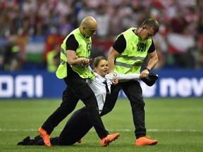 Stewards pull a woman off the pitch after she stormed onto the field and interrupted the final match between France and Croatia at the 2018 soccer World Cup in the Luzhniki Stadium in Moscow, Russia, Sunday, July 15, 2018.