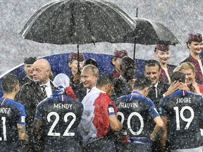 FIFA President Gianni Infantino, Russian President Vladimir Putin, French President Emmanuel Macron and Croatian President Kolinda Grabar-Kitarovic, from left, stand in the puring rain as they congratulate the French players after France won 4-2 in the final match between France and Croatia at the 2018 soccer World Cup in the Luzhniki Stadium in Moscow, Russia, Sunday, July 15, 2018.