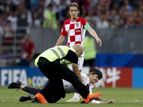 A woman is stopped by a steward after running into the pitch during the final match between France and Croatia at the 2018 soccer World Cup in the Luzhniki Stadium in Moscow, Russia, Sunday, July 15, 2018.