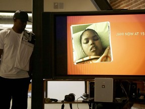 FILE - In this Dec. 23, 2015, file photo, a photo of Jahi McMath is shown on a video screen next to her uncle Timothy Whisenton at a news conference in San Francisco. The mother of a girl at the center of a medical and religious debate over brain death says she does not regret selling her home and moving to New Jersey so her daughter could receive care after being declared dead. Nailah Winkfield said at a news conference on Tuesday, July 3, 2018, that she gave up everything for her daughter Jahi McMath, but it was worthwhile. The San Francisco Chronicle reports that Jahi will be buried on Friday in Hayward, Calif.