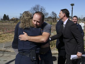 Brad Sherwood, center, hugs Rincon Valley and Windsor fire prevention officer Cyndi Foreman on his property where his home was destroyed in October 2017 by wildfires, in Santa Rosa, Calif., Wednesday, July 11, 2018. Victims of California's deadliest wildfires and local politicians are calling on state lawmakers to stop trying to overhaul the state's liability laws on wildfires.