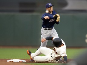 Milwaukee Brewers second baseman Brad Miller (10) throws over San Francisco Giants' Chase d'Arnaud to first to complete a double play during the first inning of a baseball game, Thursday, July 26, 2018, in San Francisco. Austin Slater was out at first base.