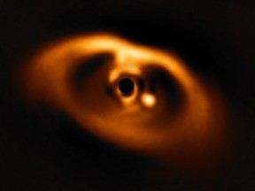 The photo provided by the European Southern Observatory ESO taken from the SPHERE instrument on ESO's Very Large Telescope is the first clear image of a planet caught in the very act of formation around the dwarf star PDS 70. The planet stands clearly out, visible as a bright point to the right of the centre of the image, which is blacked out by the coronagraph mask used to block the blinding light of the central star.