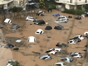 Cars in floodwater in an open parking area in northern Athens, seen through a window, Thursday, July 26, 2018, after flash floods caused by a sudden downpour.