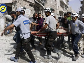 FILE - In this Wednesday, Sept. 21, 2016, file photo, provided by the Syrian Civil Defense White Helmets, rescue workers move a victim from site of airstrikes in the al-Sakhour neighborhood of the rebel-held part of eastern Aleppo, Syria. The call to get ready came at night. In the raging war zone of southwestern Syria, with enemy government forces on the march, the 98 White Helmets were told to bring spouses, children and but a few belongings to two collection points. Fabled rescuers themselves now in need of rescue, they embarked on a hair-raising journey through Israel, a supposed enemy, enroute to reluctant haven in Jordan, a country already burdened with multitudes of refugees. One woman gave birth along the way, many colleagues were left behind to a fate uncertain, and Syria called the multinational operation by several Western powers a crime.