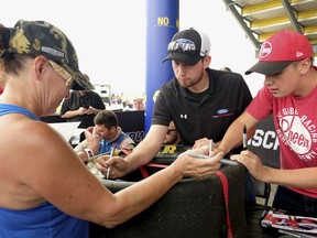 Diana Williams of Otumwa, Iowa, gets the tire she brought with her autographed by Chase Briscoe and Christopher Bell before the start of the NASCAR Xfinity Series auto race, Saturday, July 28, 2018, at Iowa Speedway in Newton, Iowa. Williams got the tire from the 2015 Iowa race off of Bubba Wallace's car after the race. "We will probably put it in the living room," said Williams. "I don't think it will go back out in the garage."