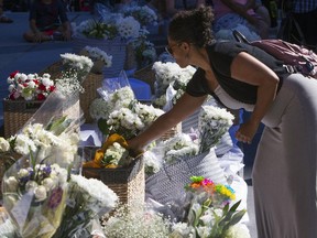 Marisol Avelar of Boise adds a bouquet of white flowers to a growing pile during a vigil at City Hall in Boise, Idaho, Monday, July 2, 2018. A 3-year-old Idaho girl who was stabbed at her birthday party died Monday, two days after a man invaded the celebration and attacked nine people with a knife, authorities said.