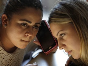 In this June 29, 2018, photo, Sirley Silveira Paixao, left, an immigrant from Brazil seeking asylum, listens on the phone with paralegal and interpreter Luana Mason to Denise Brown, director of Heartland Human Care Service, on the procedures Paixao needs to fulfill to get her son Diego released from immigration detention in Chicago. Paixao and her son arrived in this country from Brazil on May 22, and were separated shortly after. She was released on June 13 and has been living in Massachusetts. Diego was taken to Chicago.