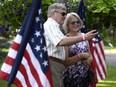 Robert Gordon and Mary Ellen Gordon take a photo beside historic American flags as they arrive at the Fourth of July Independence Day celebration at Lornado, the ambassador's official residence, in Ottawa on Wednesday, July 4, 2018.