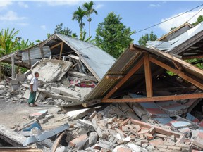 Villagers walk near destroyed homes in an area affected by the early morning earthquake at Sajang village, Sembalun, East Lombok, Indonesia, Sunday, July 29, 2018. A shallow, magnitude 6.4 earthquake early Sunday killed at least 10 people and injured 40 on Indonesia's Lombok Island, a popular tourist destination next to Bali, officials said.