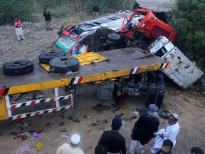 Police officers and volunteers inspect the wreckage of a vehicular accident in Matiarai, near Hyderabad, Pakistan, Monday, July 16, 2018. Police say a trailer truck collided with a parked passenger bus carrying wedding guests on a busy highway near the southern city of Hyderabad, killing  over a dozen people.