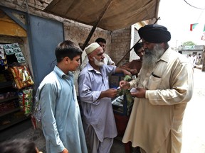 In this July 11, 2018, photo, Radesh Singh, right, is one of about 200,000 Sikhs living in Pakistan, talks to local people in his constituency in Peshawar, Pakistan. Despite attacks on his fellow Sikhs by radicals and even by Islamic State insurgents, he is running in elections as an independent.