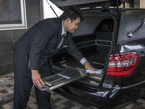 A Tear Corp. driver cleans the back of a Mercedes-Benz hearse outside the company's headquarters in Nagoya, Japan, on June 20, 2018.