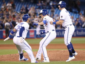 Aledmys Diaz, centre, is congratulated by teammates Devon Travis, left, and Randal Crichuk after his game-winning single in the 10th inning of Friday's 8-7 victory by the Toronto Blue Jays over the Baltimore Orioles at Rogers Centre. Diaz had four hits on the night including a homerun.
