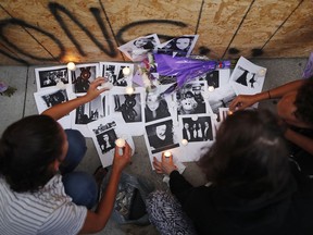 People light candles and leave photos of 18-year-old victim Reese Fallon at a memorial remembering the victims of a shooting on Sunday evening on Danforth, Ave. in Toronto on Monday, July 23, 2018.