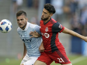 Sporting Kansas City forward Diego Rubio, left, works against Toronto FC midfielder Jonathan Osorio (21) during the first half of an MLS soccer match in Kansas City, Kan., Saturday, July 7, 2018.