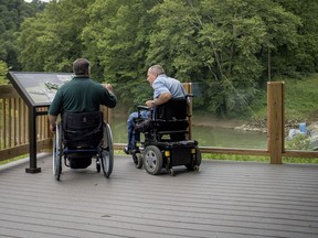 David Allgood and Tom Stokes overlook the Green River from a trail adapted for persons with disabilities at Mammoth Cave National Park in Cave City, Ky., Friday, June 22, 2018.  National Park Service accessibility chief Jeremy Buzzell says nine parks across the U.S. have received more than $10 million in federal funding to design and build accessibility projects as examples for other parks.