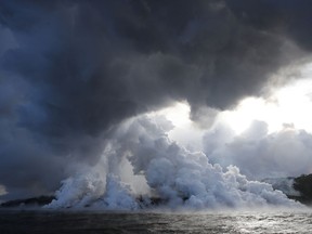 FILE - In this May 20, 2018 file photo, plumes of steam rise as lava enters the ocean near Pahoa, Hawaii. An explosion sent lava flying through the roof of a tour boat off Hawaii's Big Island, injuring at least 13 people Monday, July 16, 2018, officials said. The people were aboard a tour boat that takes visitors to see lava from an erupting volcano plunge into the ocean.