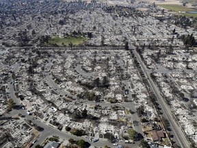 FILE - This Oct. 14, 2017 file photo shows an aerial view shows the devastation of the Coffey Park neighborhood after the Tubbs swept through in Santa Rosa, Calif.  In the last year, fires have devastated neighborhoods in the Northern California wine country city of Santa Rosa, the Southern California beach city of Ventura and, now, the inland city of Redding. Hotter weather from changing climates is drying out vegetation, creating more intense fires that spread quickly from rural areas to city subdivisions, climate and fire experts say. But they also blame cities for expanding into previously undeveloped areas susceptible to fire.