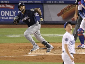 Milwaukee Brewers' Eric Thames, left, runs to first as he hits a three-run home run while Los Angeles Dodgers starting pitcher Kenta Maeda, of Japan, watches during the third inning of a baseball game, Monday, July 30, 2018, in Los Angeles.