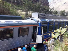 In this photo provided by the government news agency Andina, passeners observe two trains after they collided in Cuzco, Peru, Tuesday, July 31, 2018. The two trains collided near the ancient Incan citadel of Machu Picchu, a prized archaeological site in Peru visited by thousands of tourists each year.