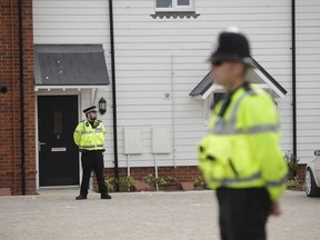 British police officers stand outside the front door of a residential property in Amesbury, England, Wednesday, July 4, 2018. British police have declared a "major incident" after two people were exposed to an unknown substance in the town, and are cordoning off places the people are known to have visited before falling ill.