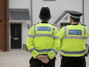 British police officers stand facing a residential property in Amesbury, England, Wednesday, July 4, 2018. British police have declared a "major incident" after two people were exposed to an unknown substance in the town, and are cordoning off places the people are known to have visited before falling ill.