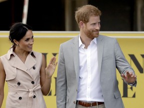 Britain's Prince Harry, right,  and his wife Meghan the Duchess of Sussex wave at onlookers as they arrive for their visit to the launch of the Nelson Mandela Centenary Exhibition, marking the 100th anniversary of anti-apartheid leader's birth, at the Queen Elizabeth Hall in London, Tuesday, July 17, 2018.