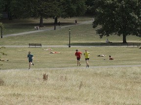 Joggers run past parched grass from the lack of rain on Primrose Hill during what has been the driest summer for many years in London, Wednesday, July 25, 2018. Britain is experiencing a severe heatwave which has prompted its national weather service to issue an alert for people to 'stay out of the sun'.